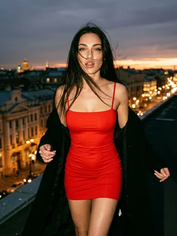 Lily in a red dress on a city rooftop at night